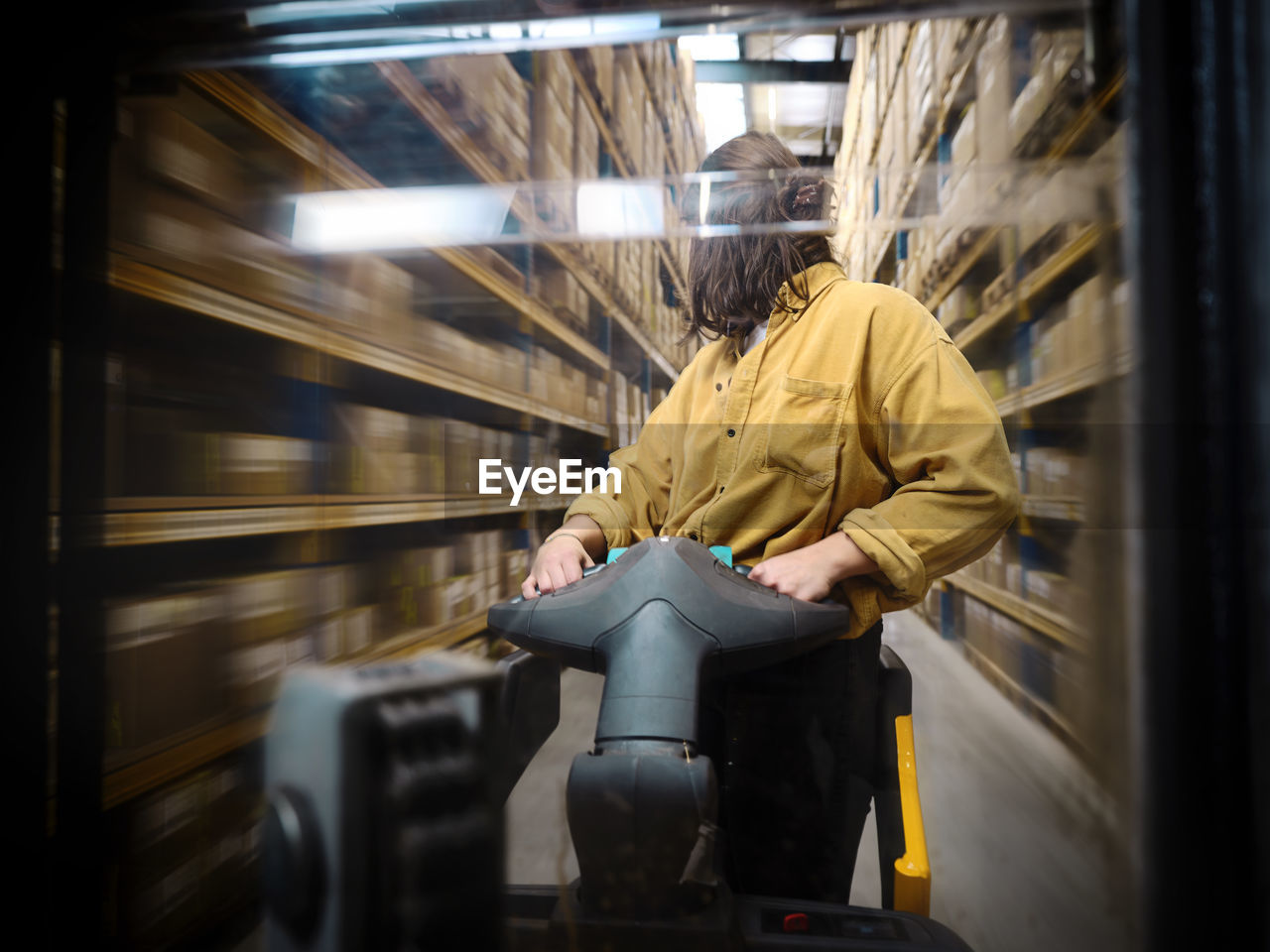 Warehouse worker looking back pushing hand truck in alley