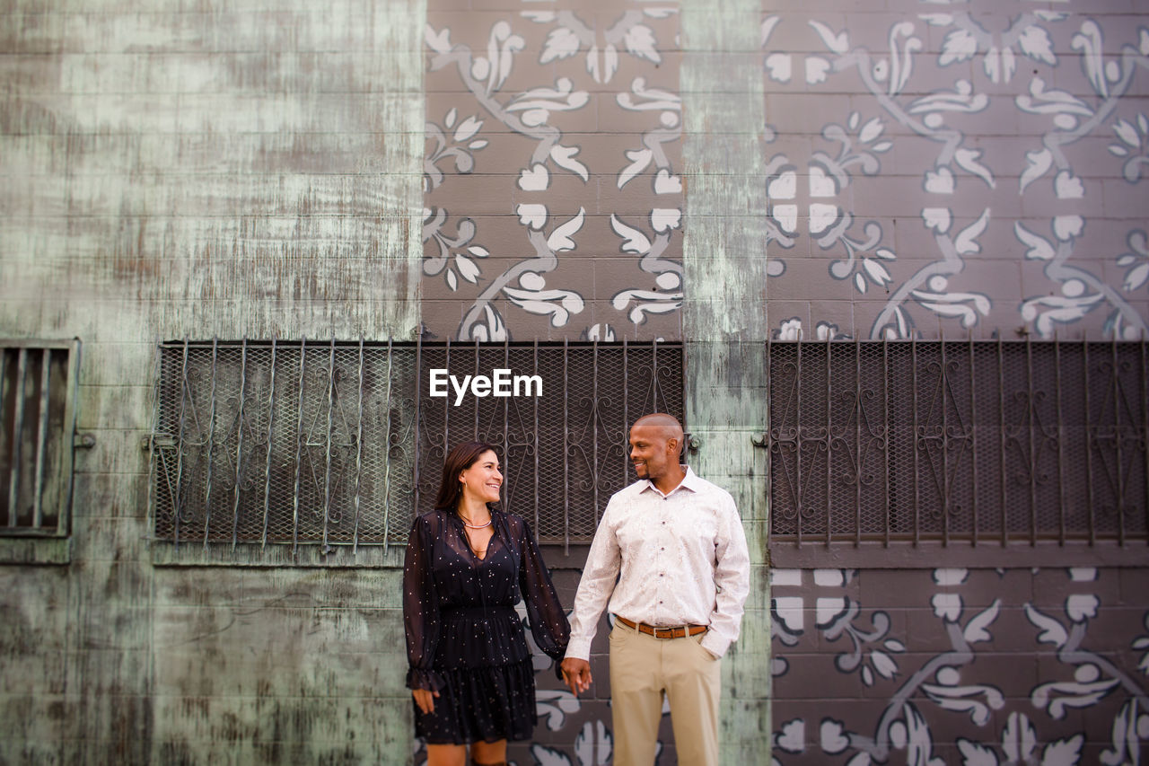 Late forties couple standing in front of mural in san diego