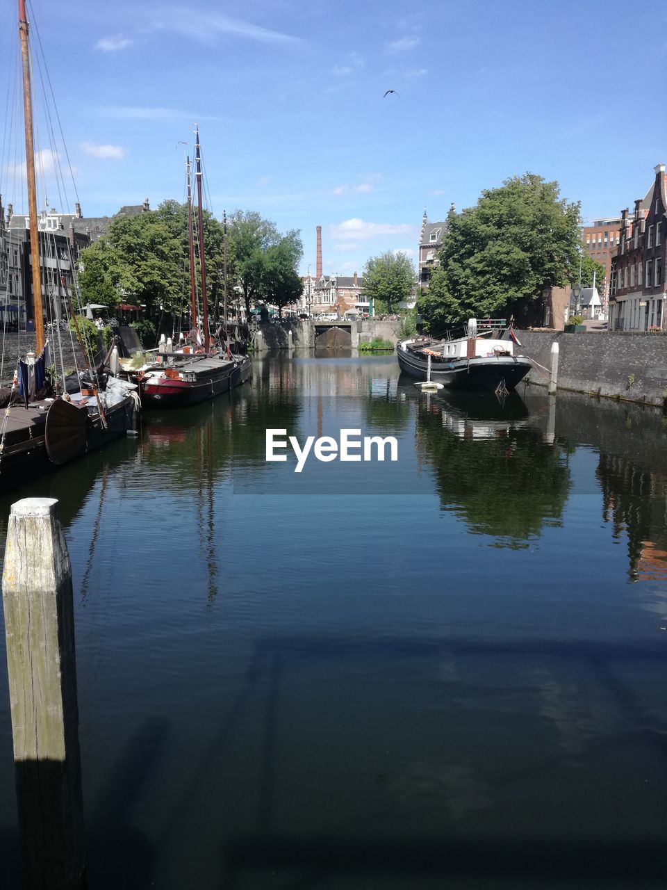 Boats moored in river by city against sky