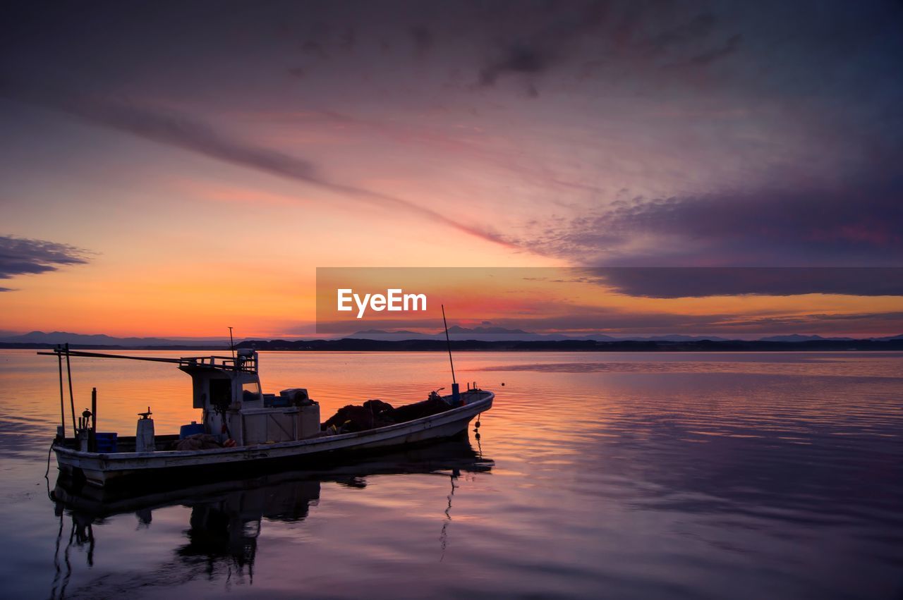 Lone boat in calm sea against scenic sky