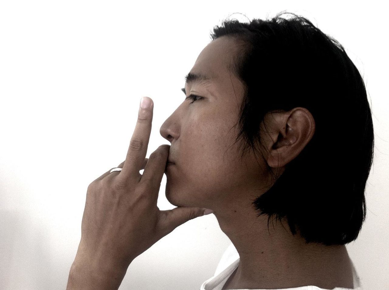Profile view of young man showing middle finger against white background