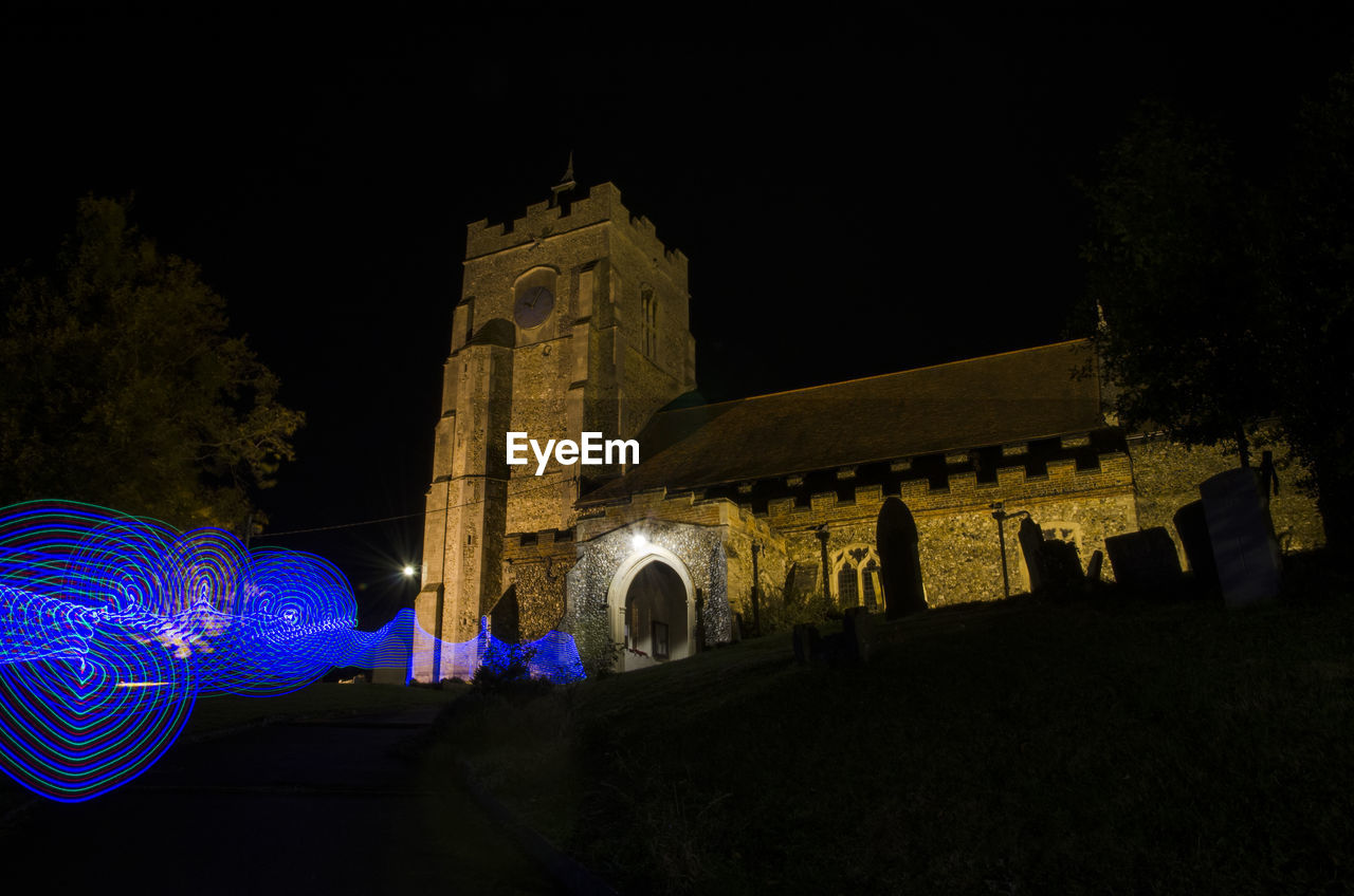 LOW ANGLE VIEW OF ILLUMINATED BUILDING AT NIGHT