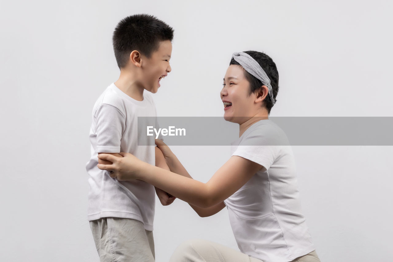 SIDE VIEW OF FATHER AND DAUGHTER AGAINST WHITE BACKGROUND