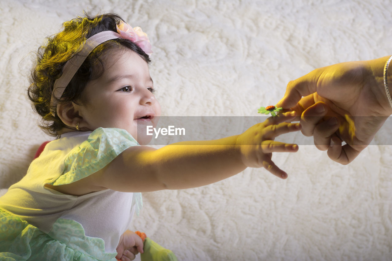 Cropped hand of person hand giving flower to baby girl at home