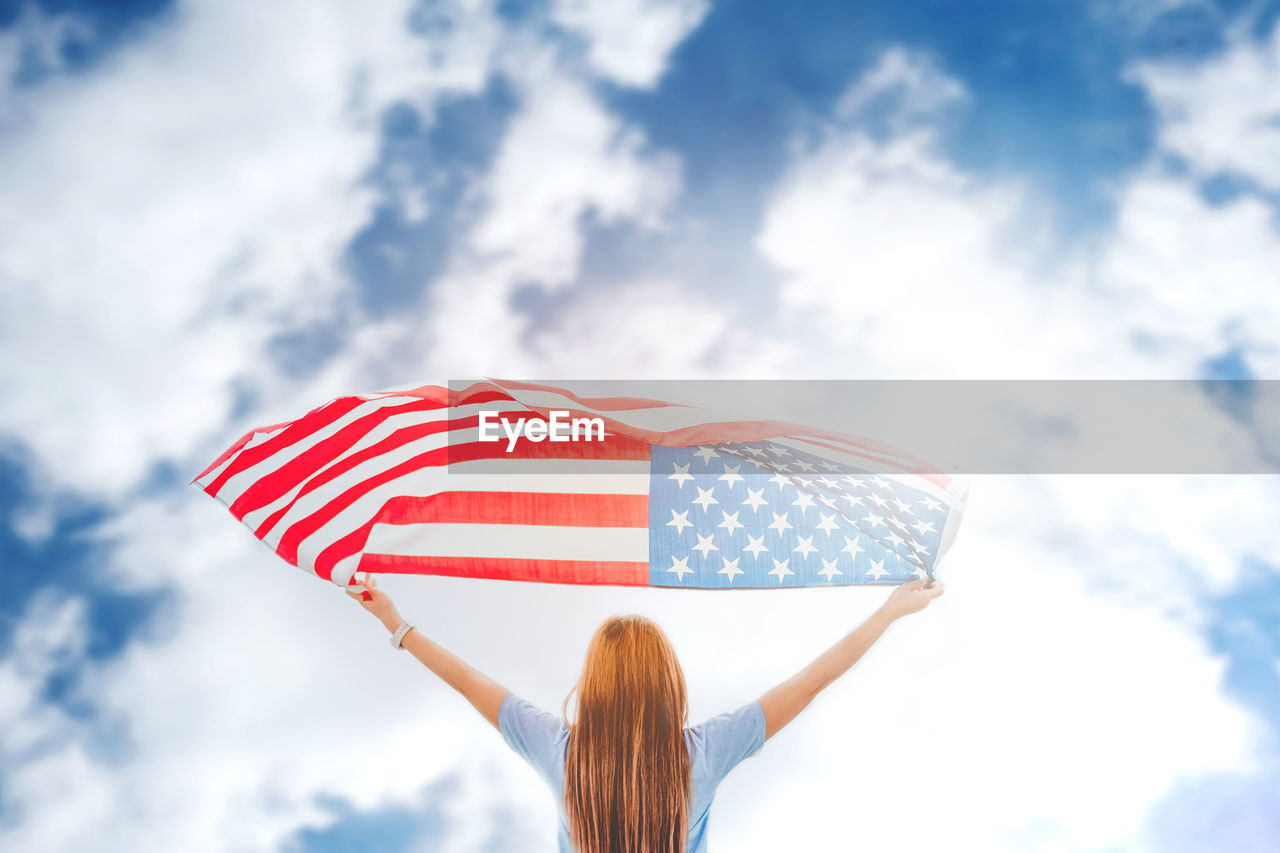 Woman with american flag standing against sky
