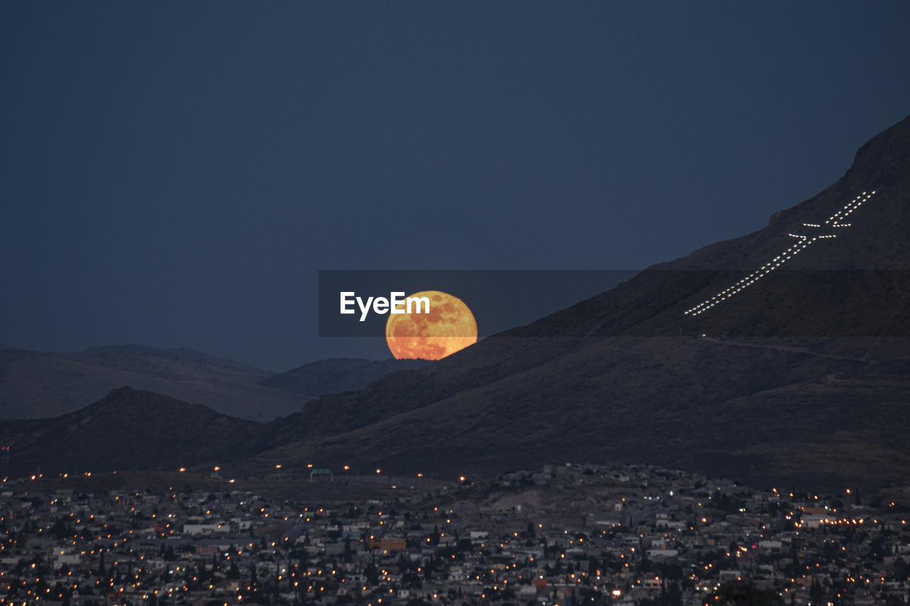 Aerial view of moonrise and illuminated cityscape against sky  at night