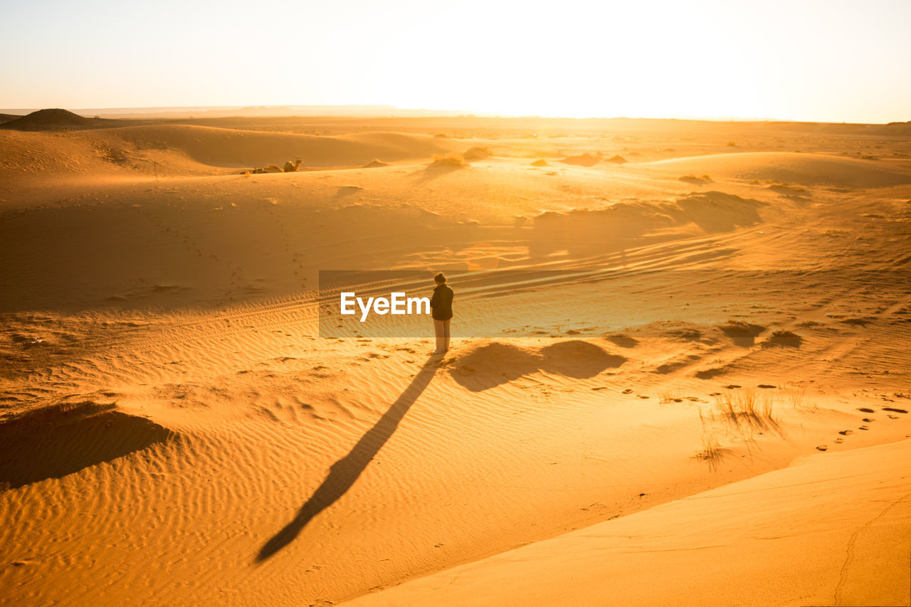 Woman alone in the desert between dunes at sunrise