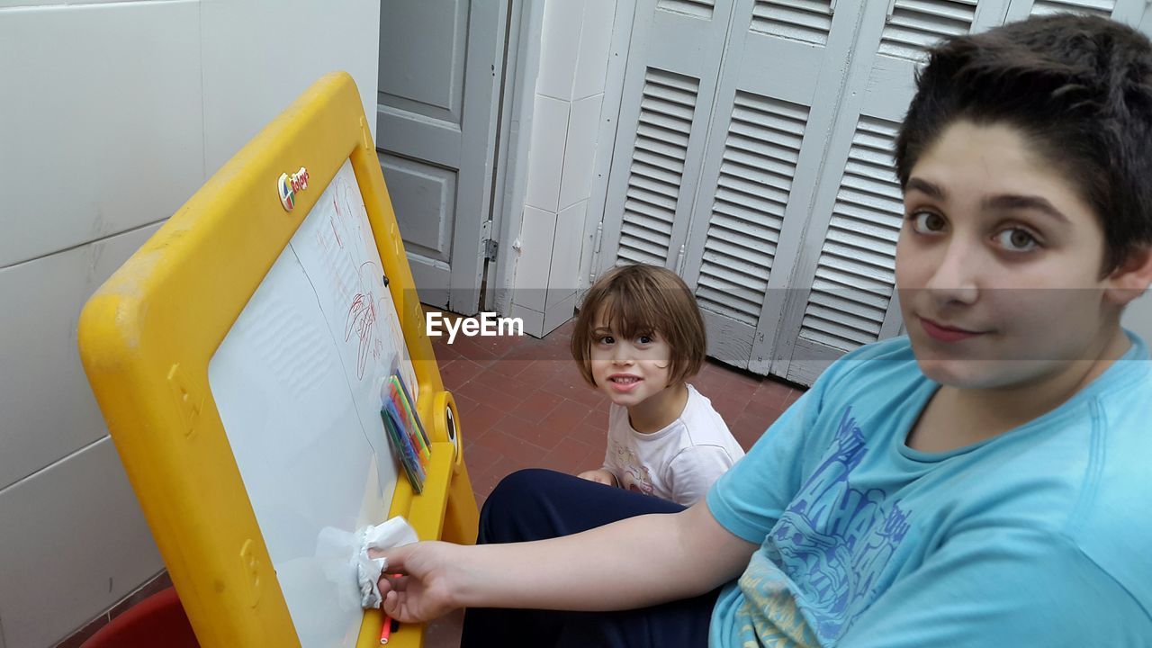 Portrait of happy girl watching his brother drawing