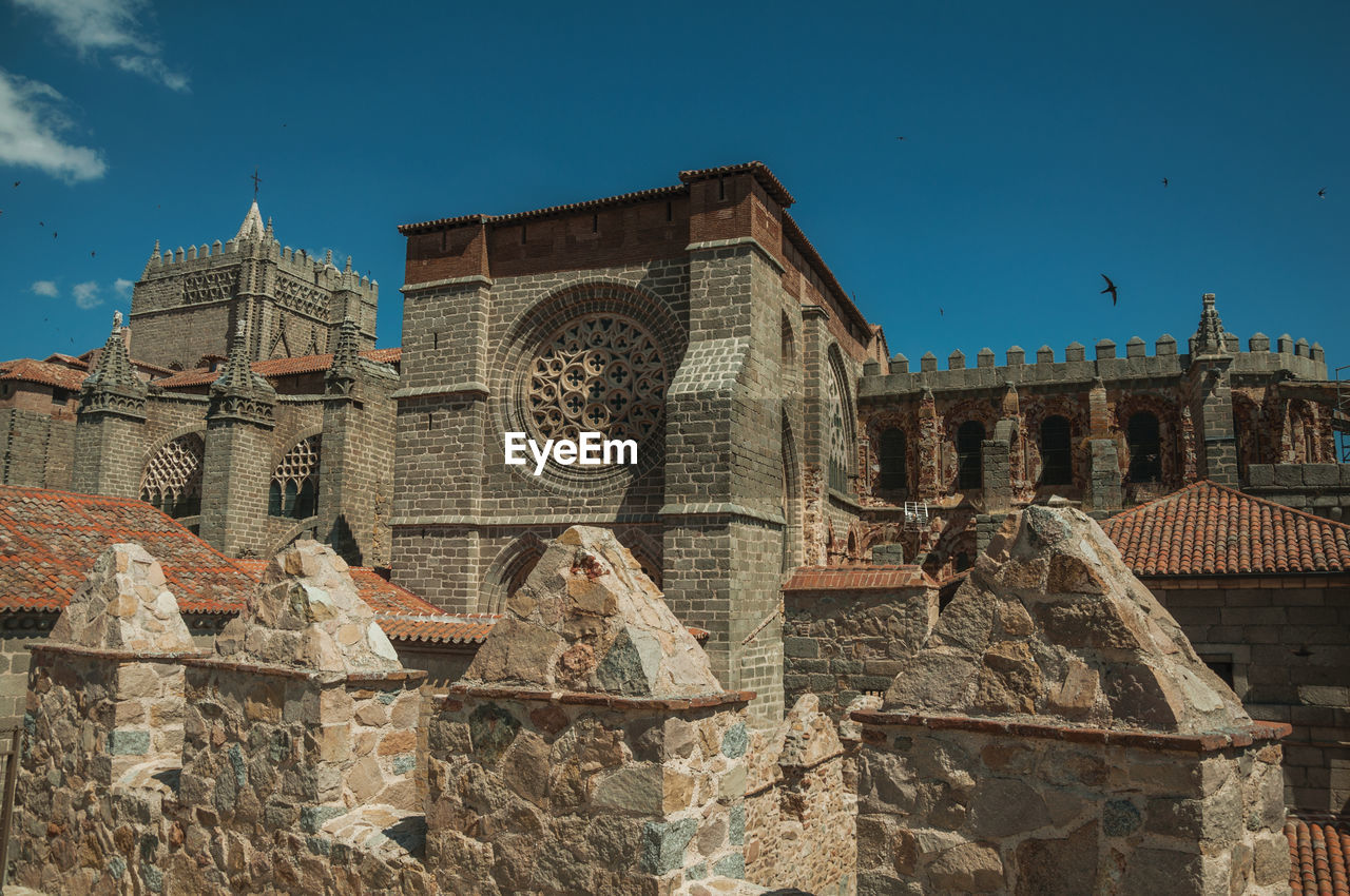 Stone thick wall with battlement and merlons encircling the town next the cathedral of avila, spain.