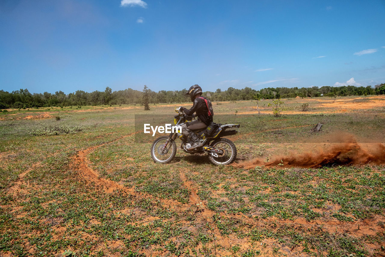 MAN RIDING MOTORCYCLE ON FIELD