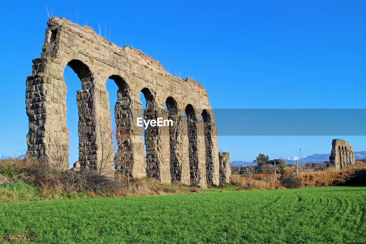 Built structure on field against clear blue sky