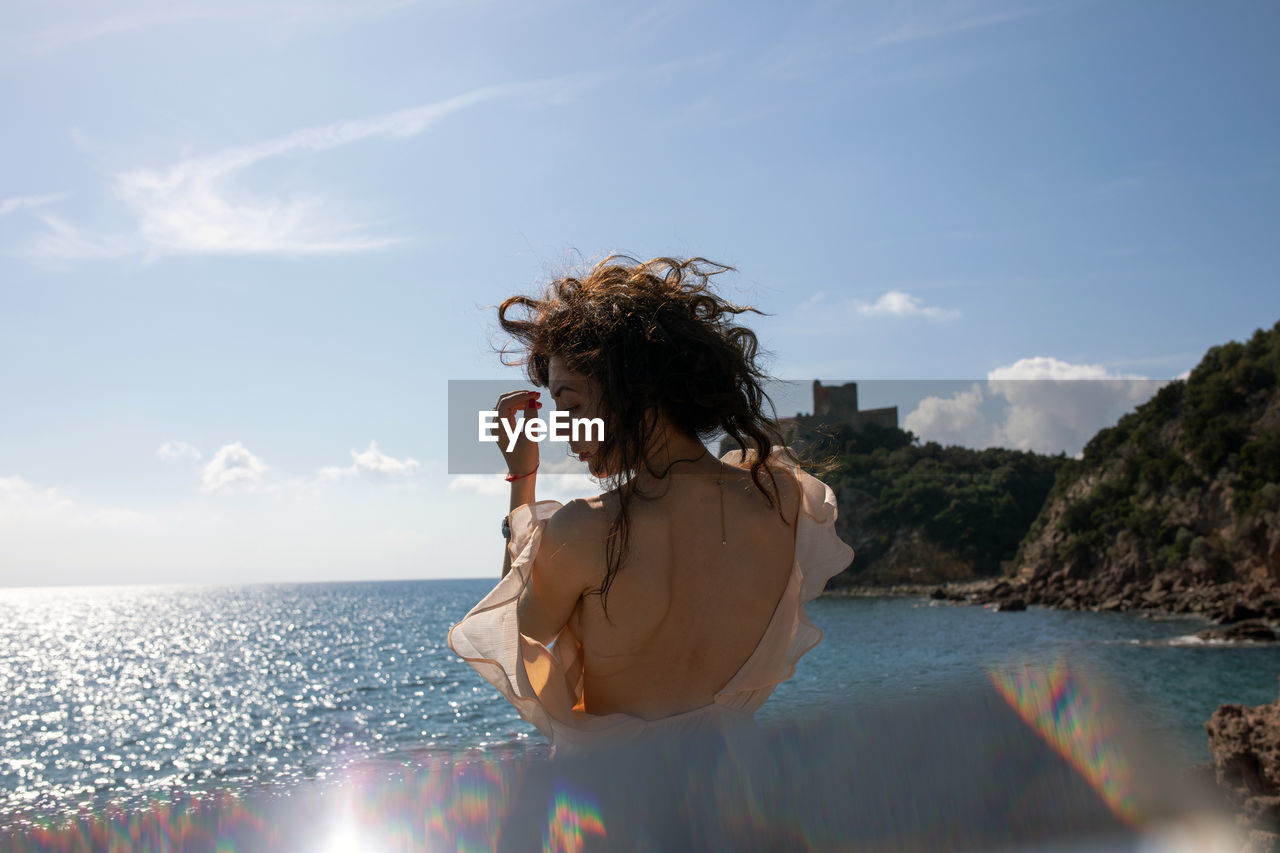 Woman by sea against sky
