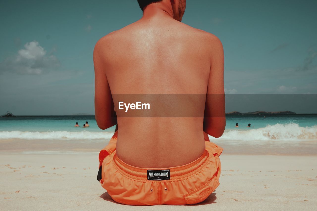 Rear view of shirtless man standing on beach