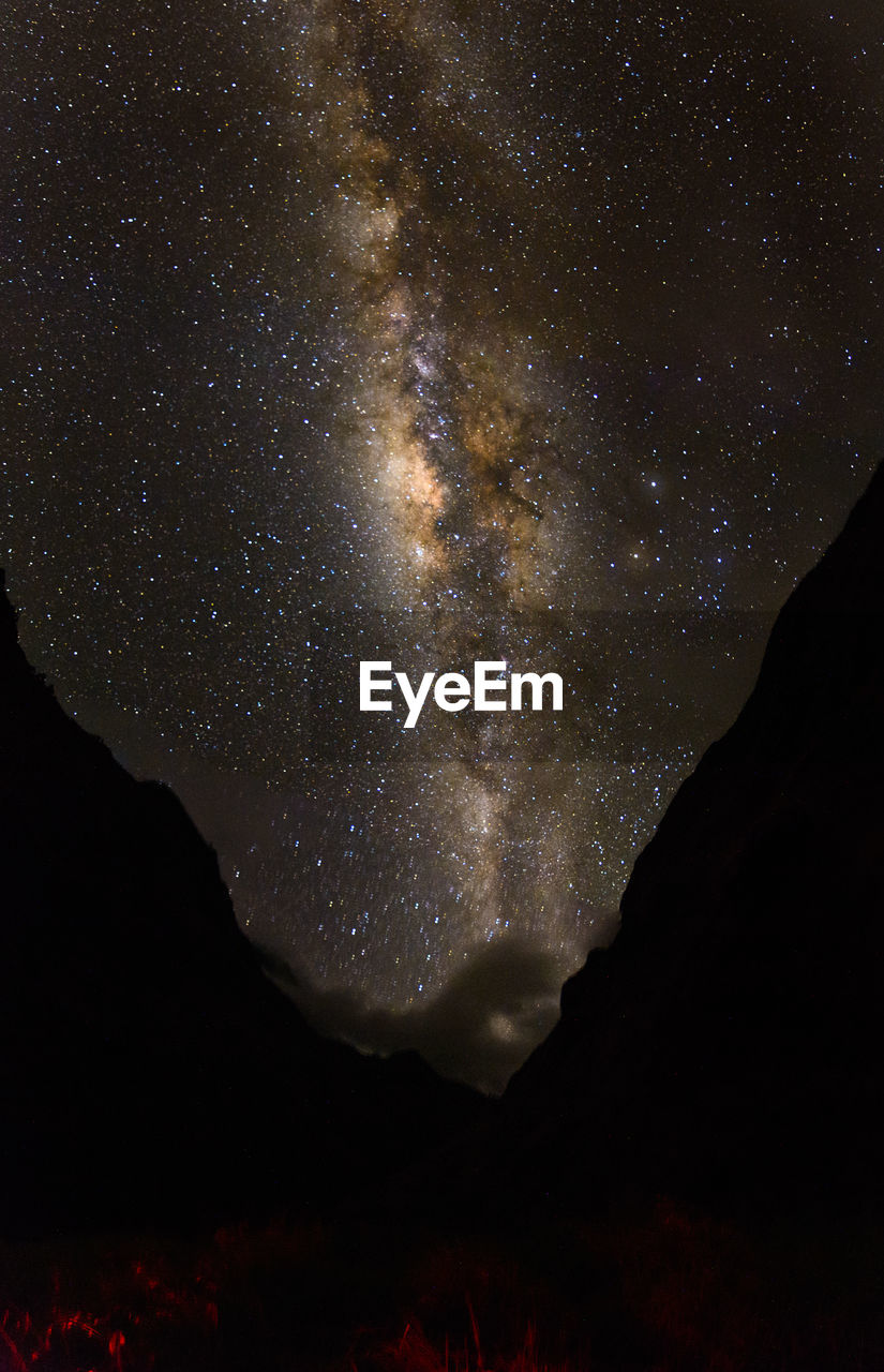 Silhouette mountain against star field at night