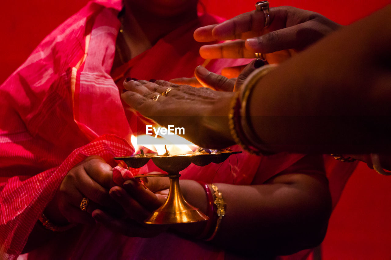 MIDSECTION OF WOMAN HOLDING HANDS WITH RED BURNING