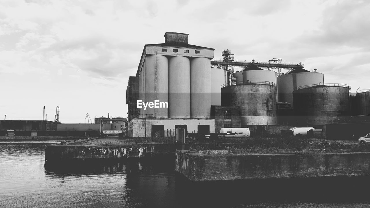 Old factory by river against sky