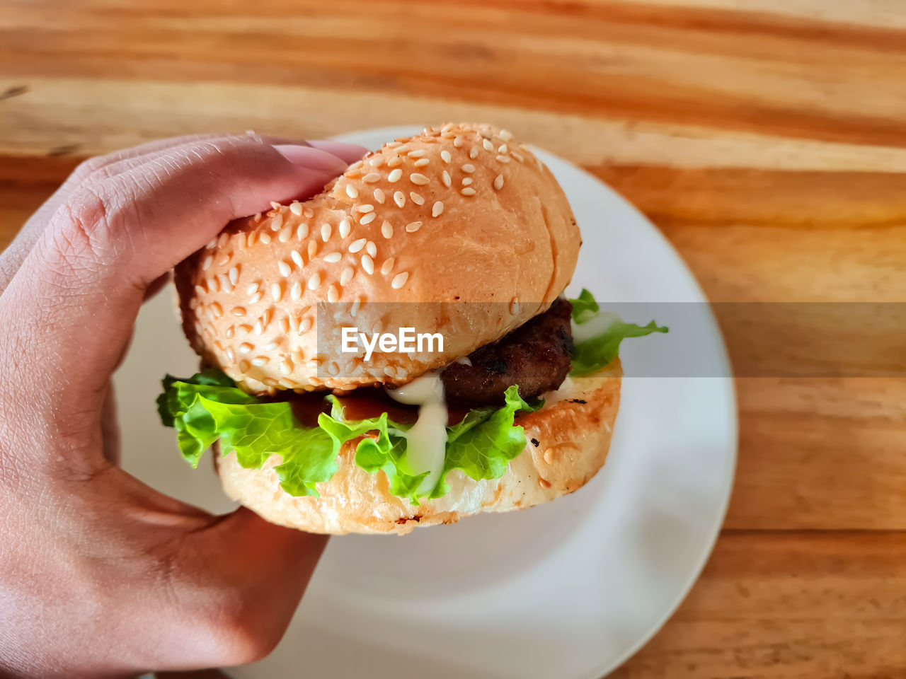 Side view burger with beef cutlet, lettuce, and sauce, ready to eat.