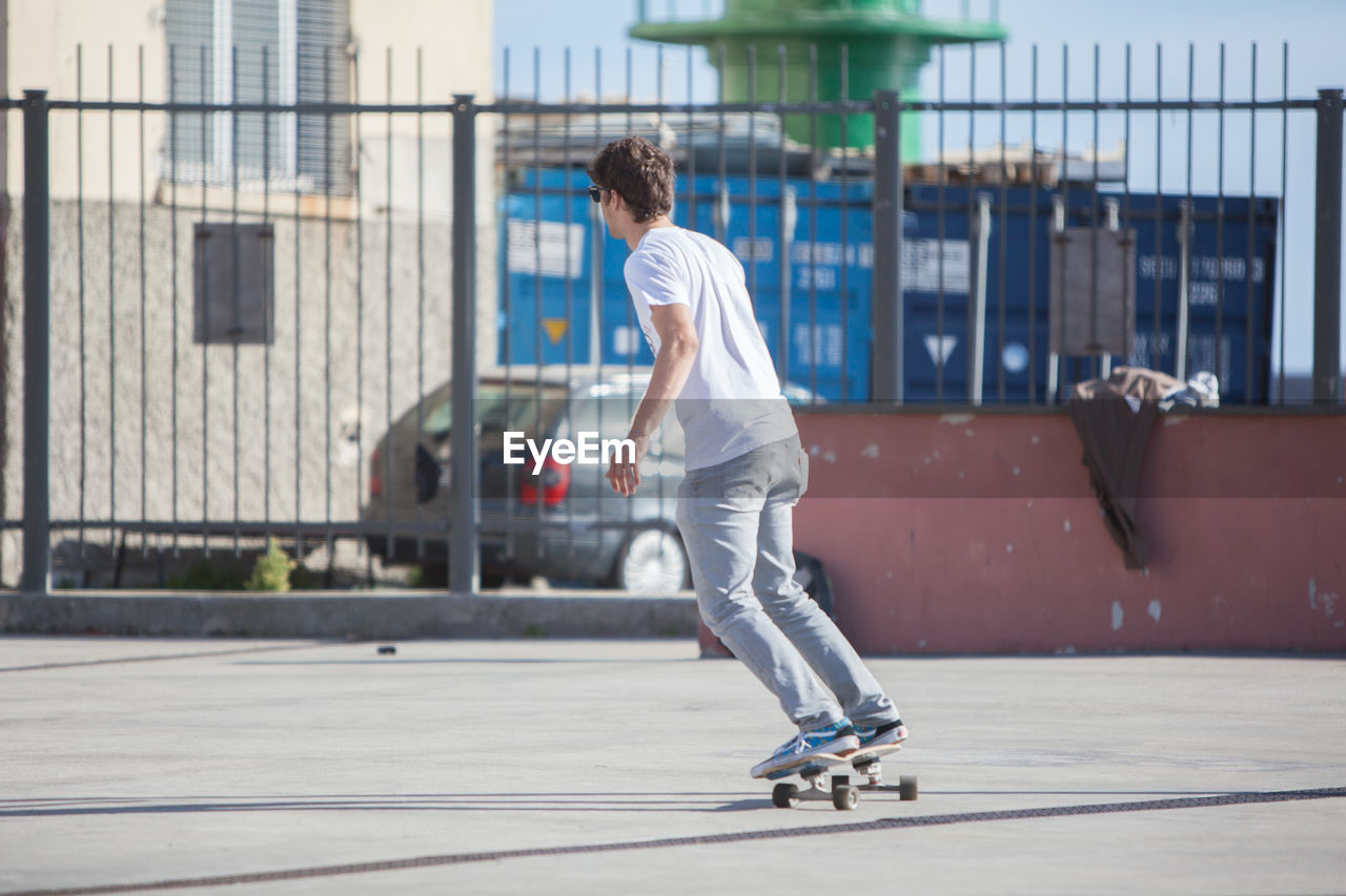 Young man skateboarding on footpath on sunny day