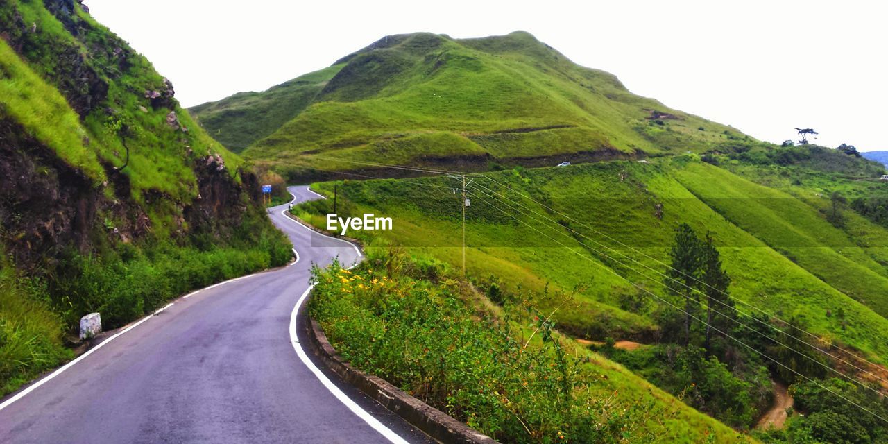 Scenic view of road amidst mountains against clear sky