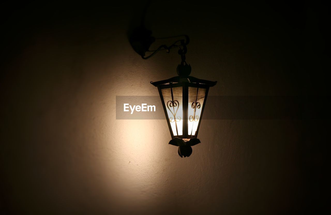 CLOSE-UP OF ILLUMINATED LIGHT BULB HANGING