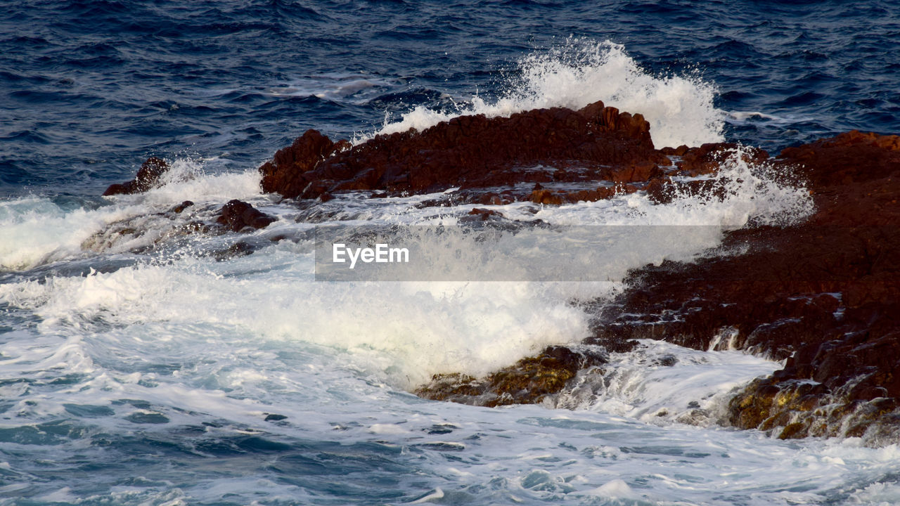 WAVES SPLASHING ON ROCKS AT SEA