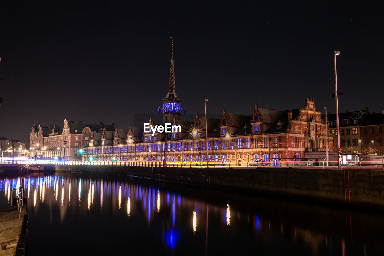 ILLUMINATED BUILDINGS BY RIVER AT NIGHT