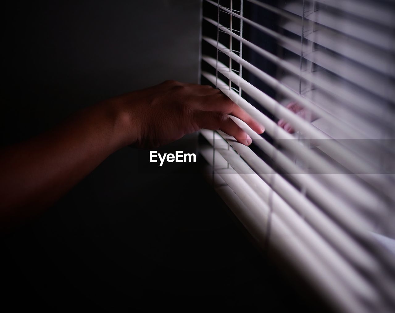 Cropped hand on blinds at home