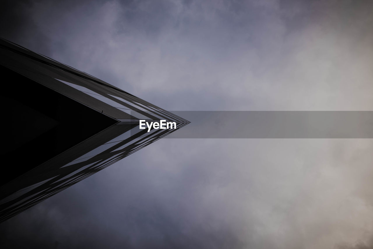 Directly below view of modern building against cloudy sky