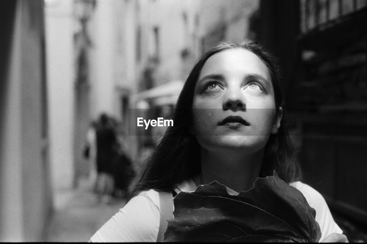 Close-up of woman looking up in city