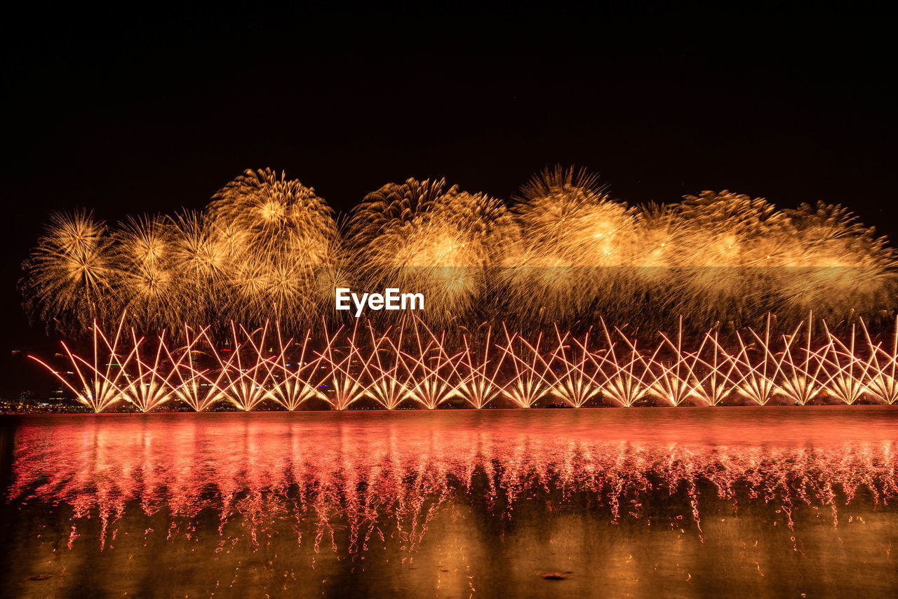 Firework display over river against sky at night