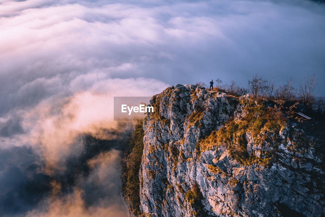 High angle view of man standing on mountain ridge rising above the clouds, hallein, austria