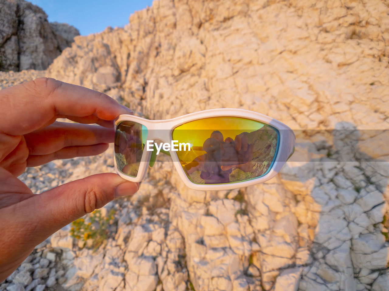 Cropped hand of man holding sunglasses with reflection