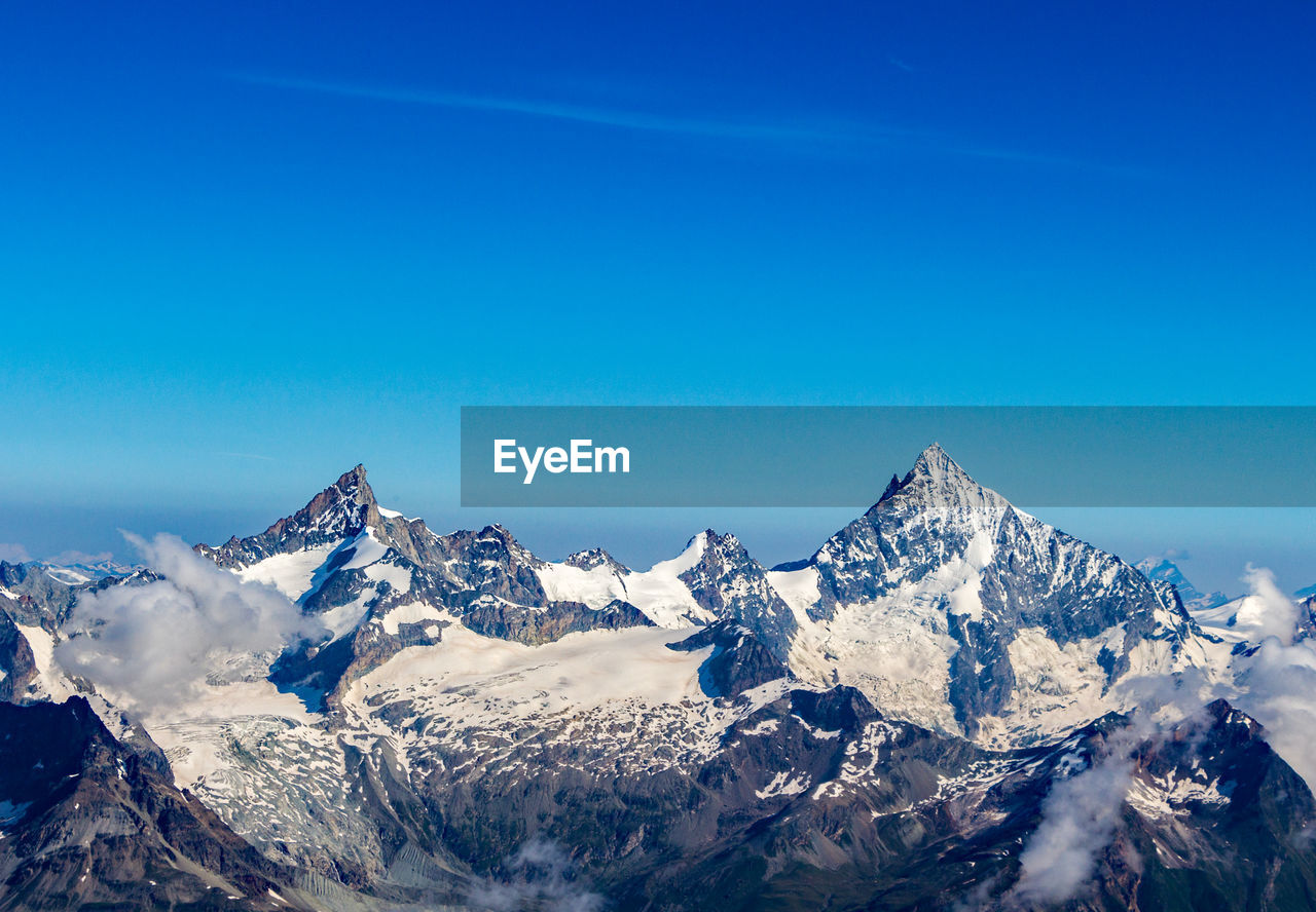Scenic view of snowcapped mountains against clear blue sky