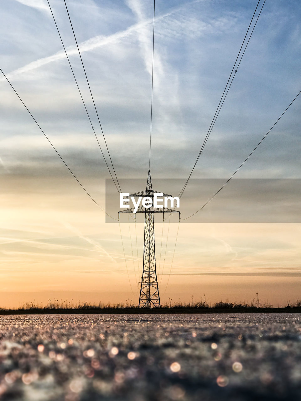 Low angle view of electricity pylon against sky during sunset