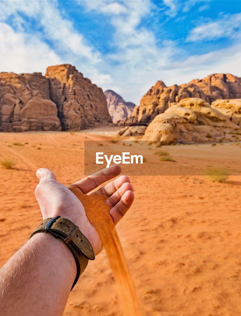 Man holding sand against sky