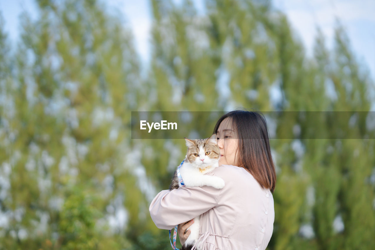 Woman embracing cat outdoors