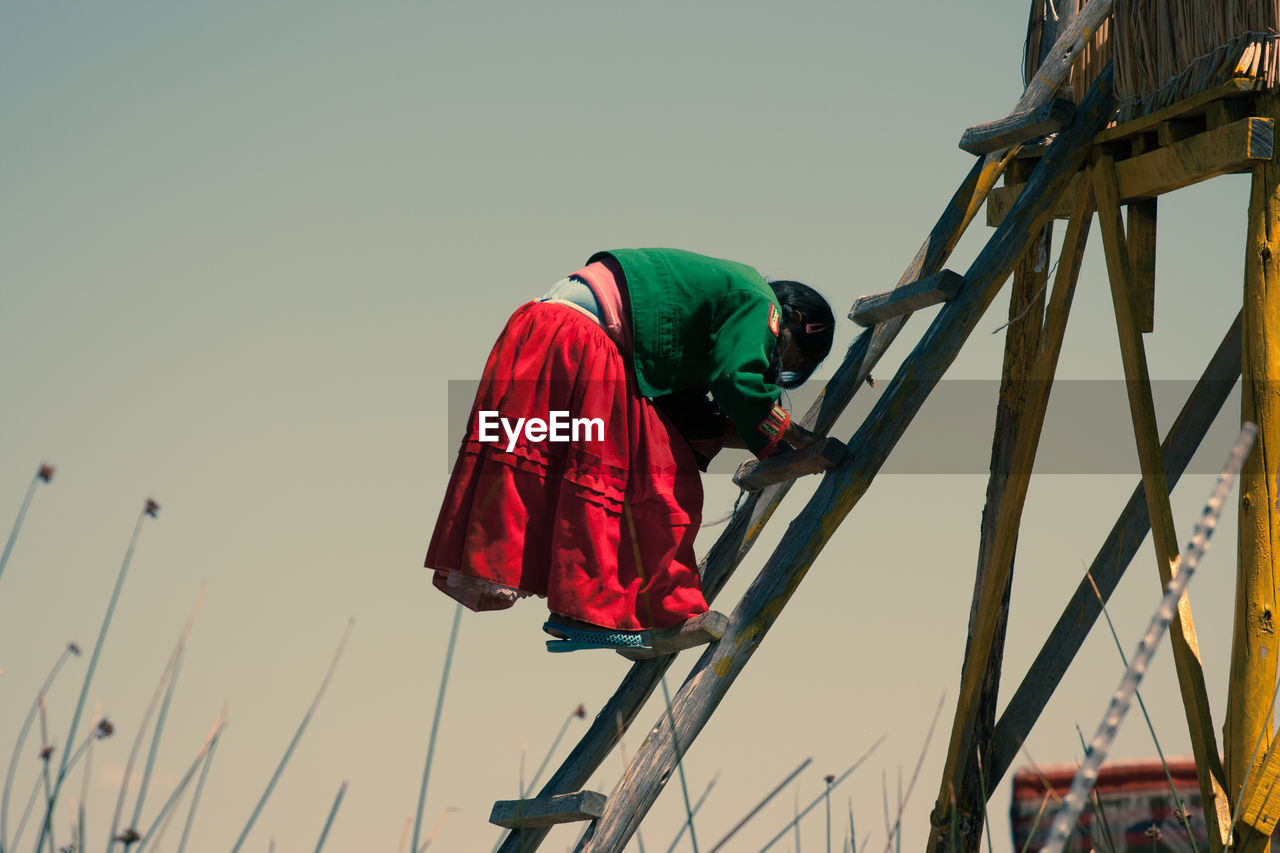 LOW ANGLE VIEW OF MEN WORKING AGAINST SKY