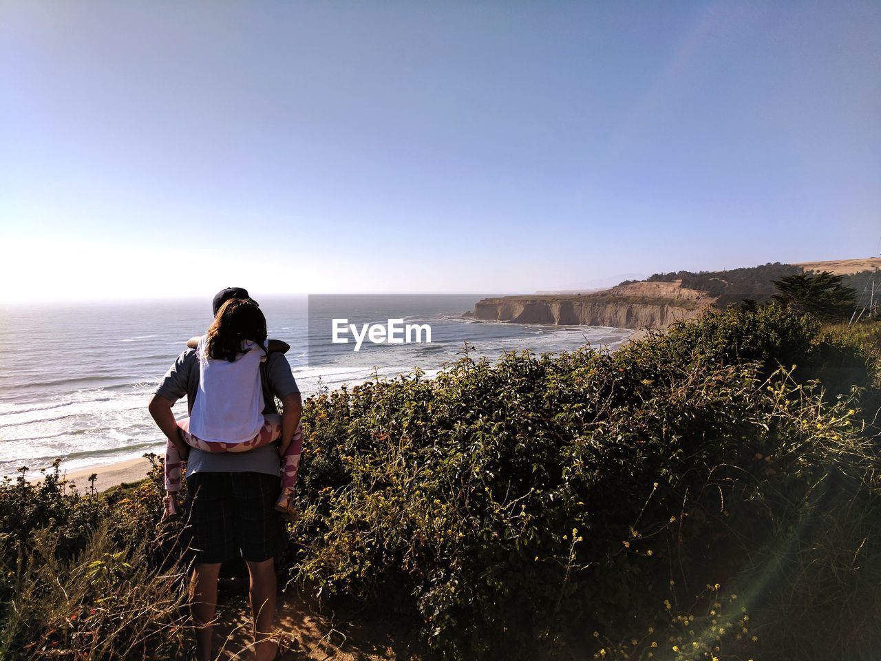 WOMAN STANDING AT BEACH AGAINST SKY