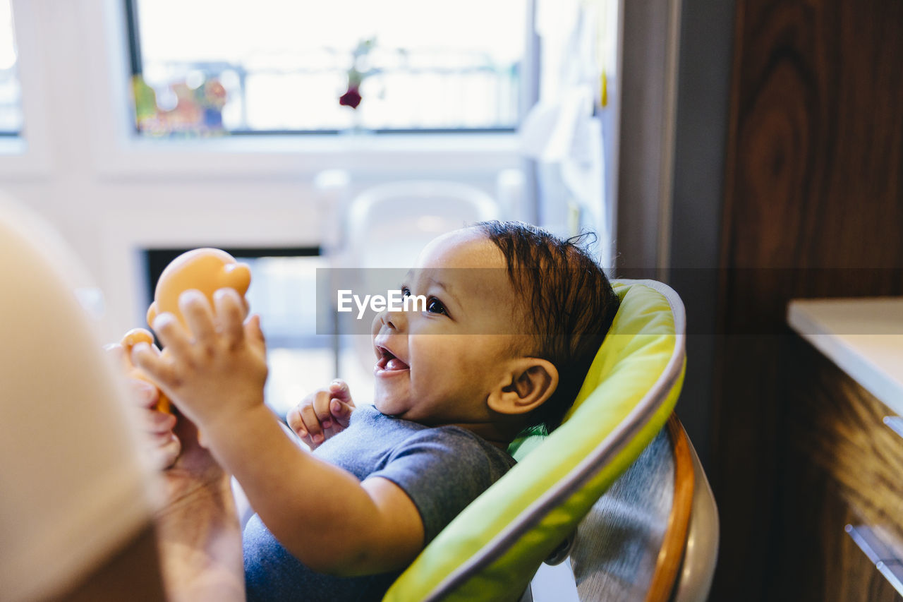 Close-up of happy boy sitting on high chair at home