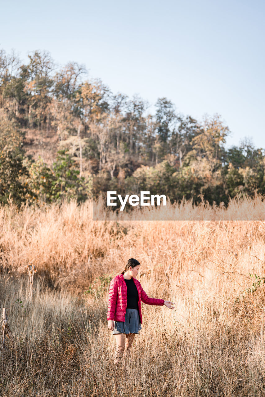 Woman standing in meadow against forest