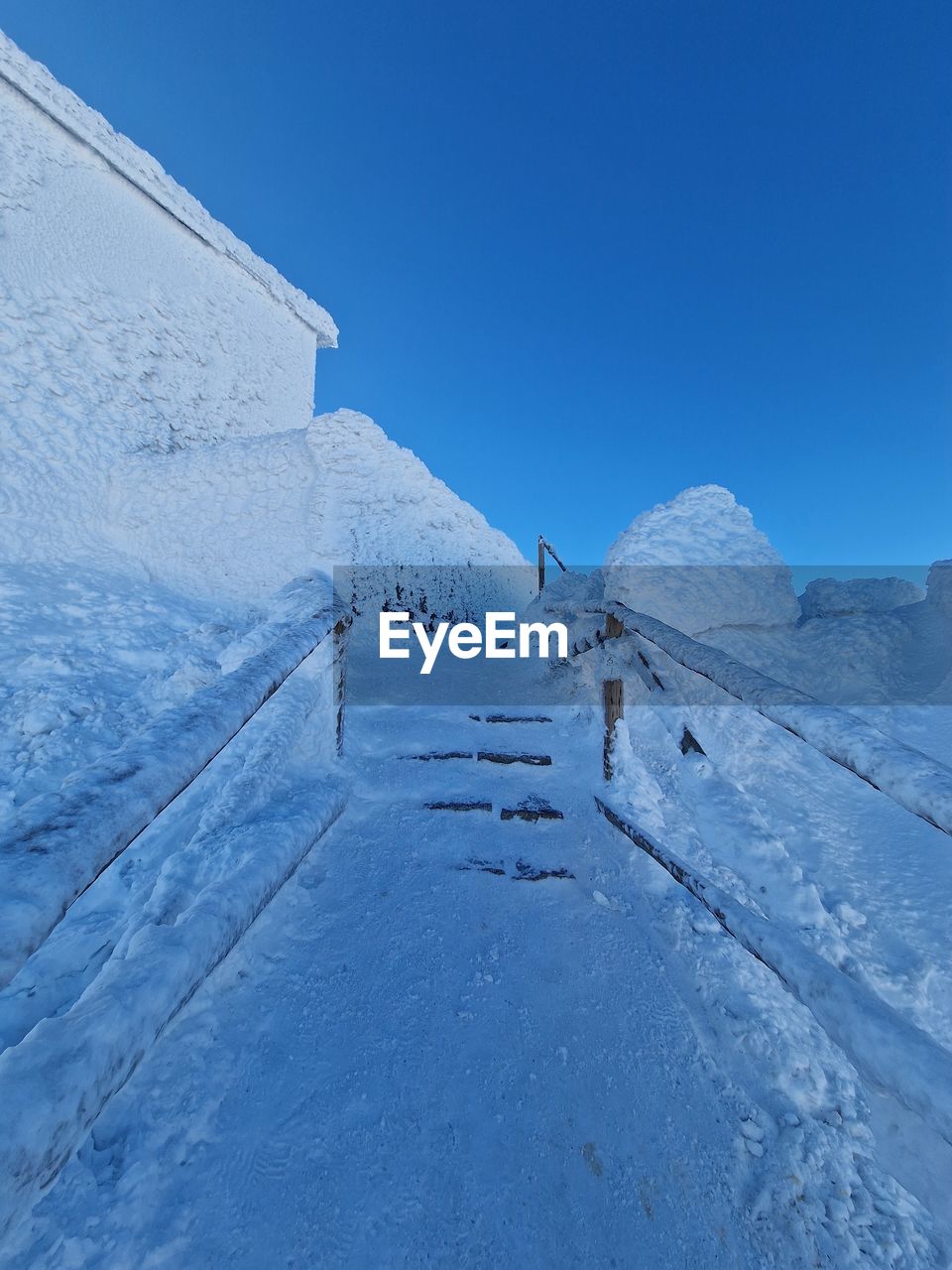 low angle view of snow covered landscape against clear blue sky