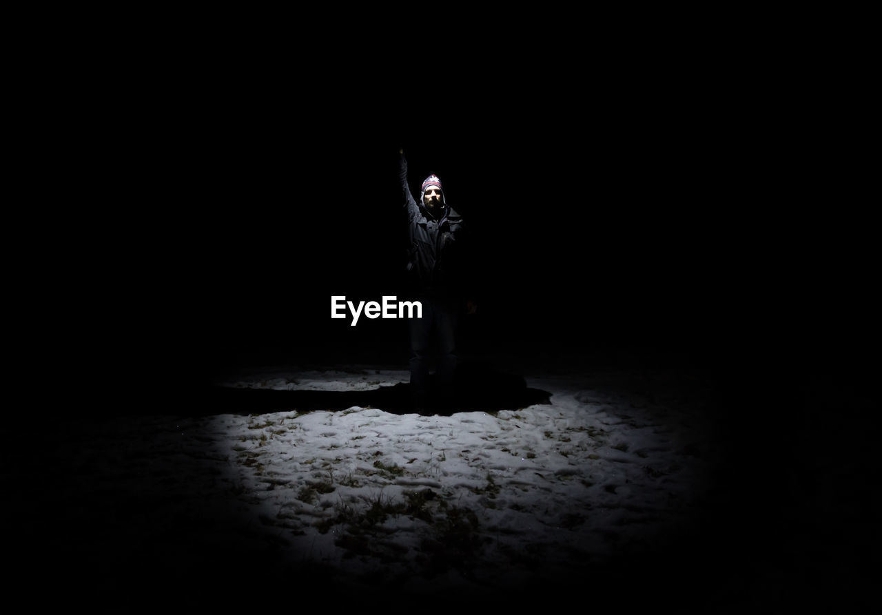 Man standing on snow covered field against clear sky at night