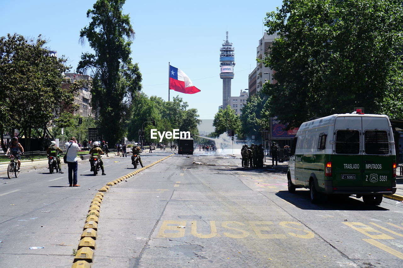 Road signal by city street against sky