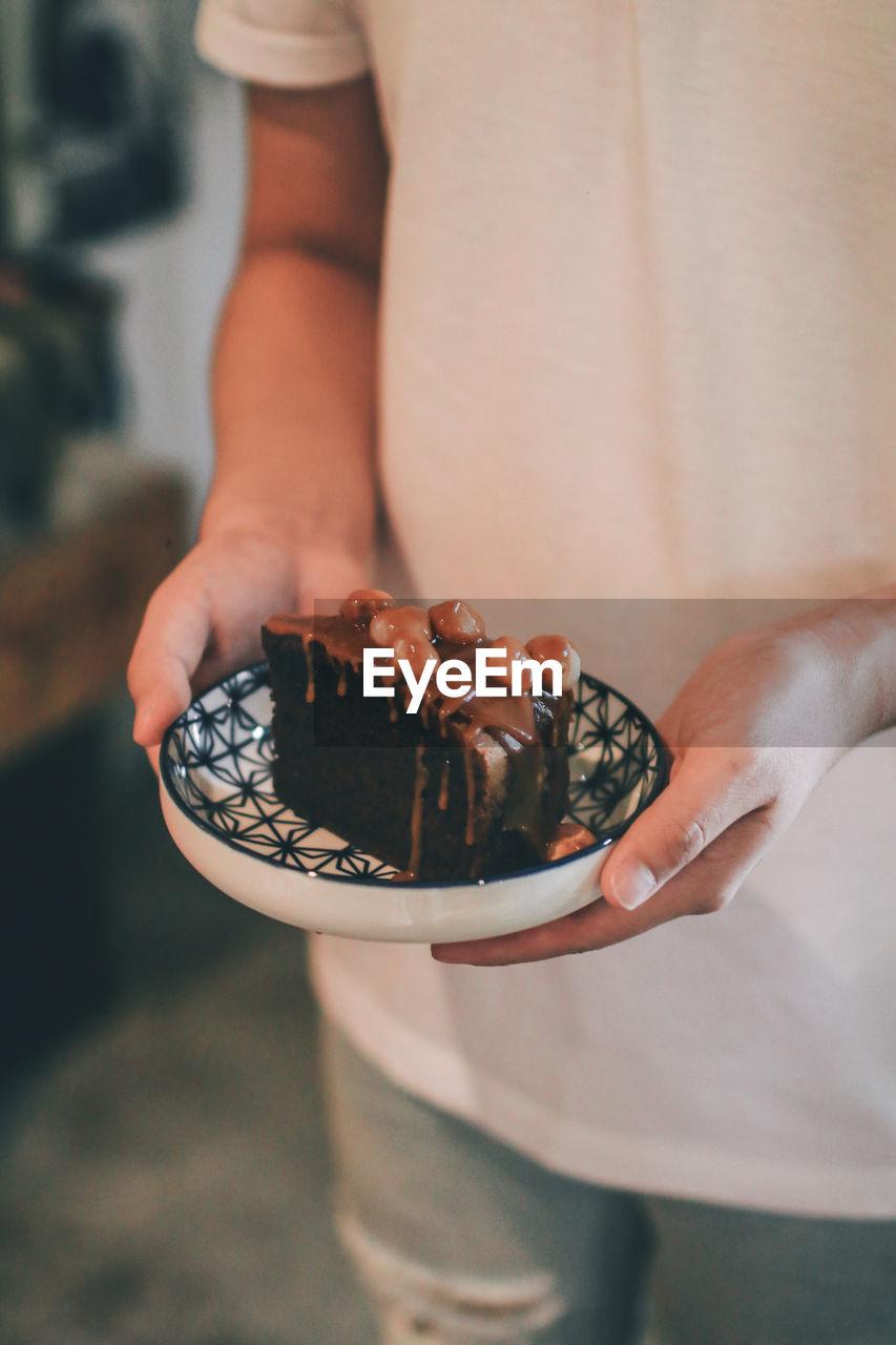 Midsection of woman holding pastry in plate