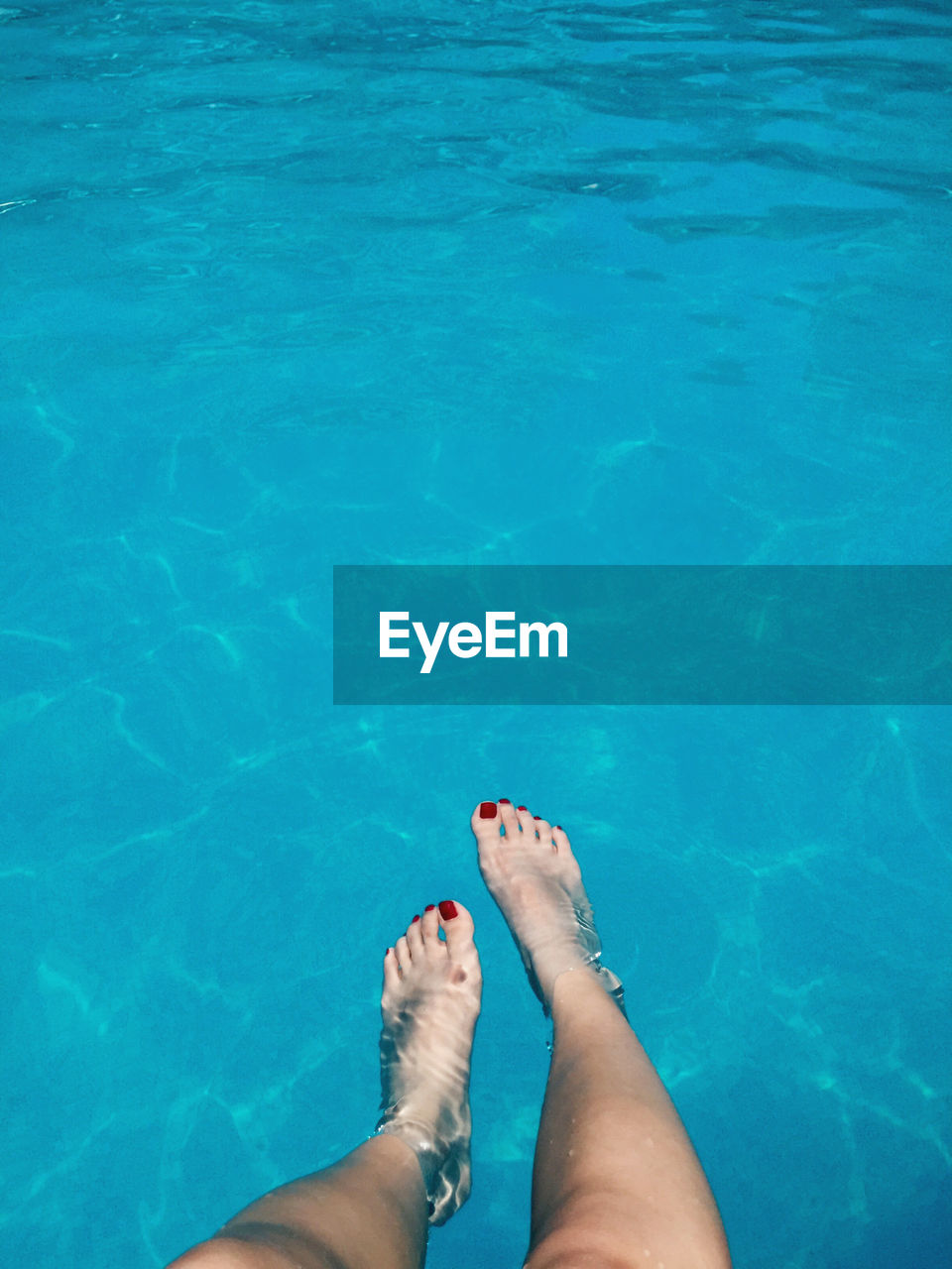 Low section of woman legs in blue swimming pool