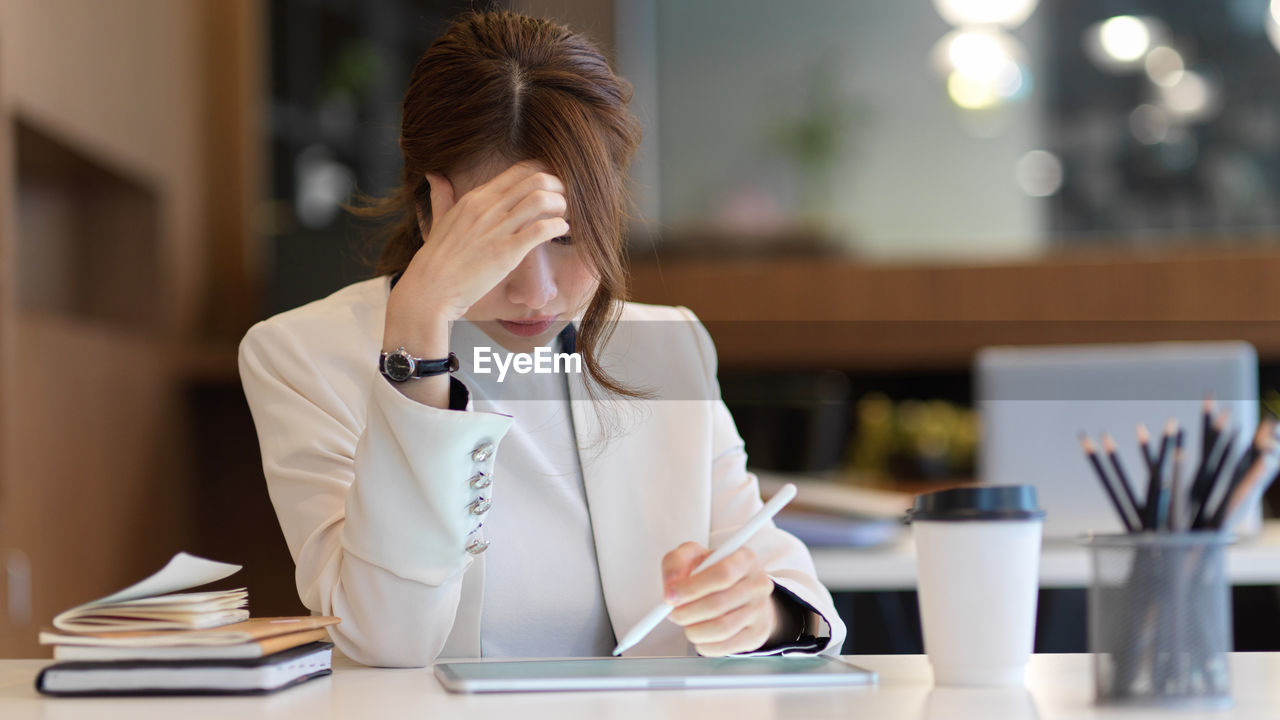 Midsection of woman using mobile phone while sitting on table