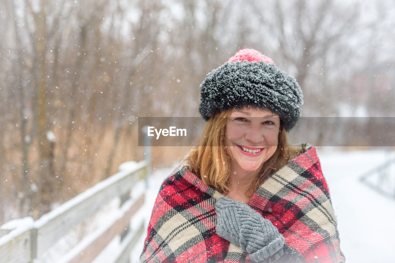 Close-up portrait of smiling woman during snowfall