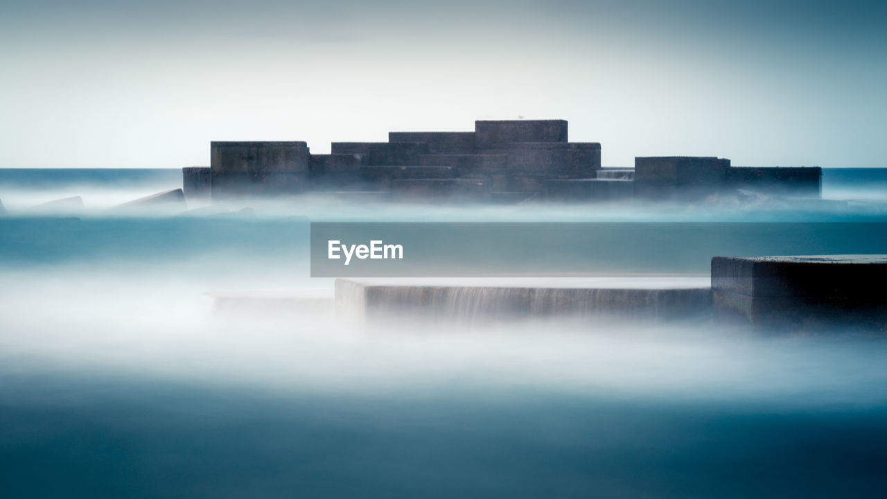 Majestic scenery of medieval stone buildings surrounded by thick mist in long exposure