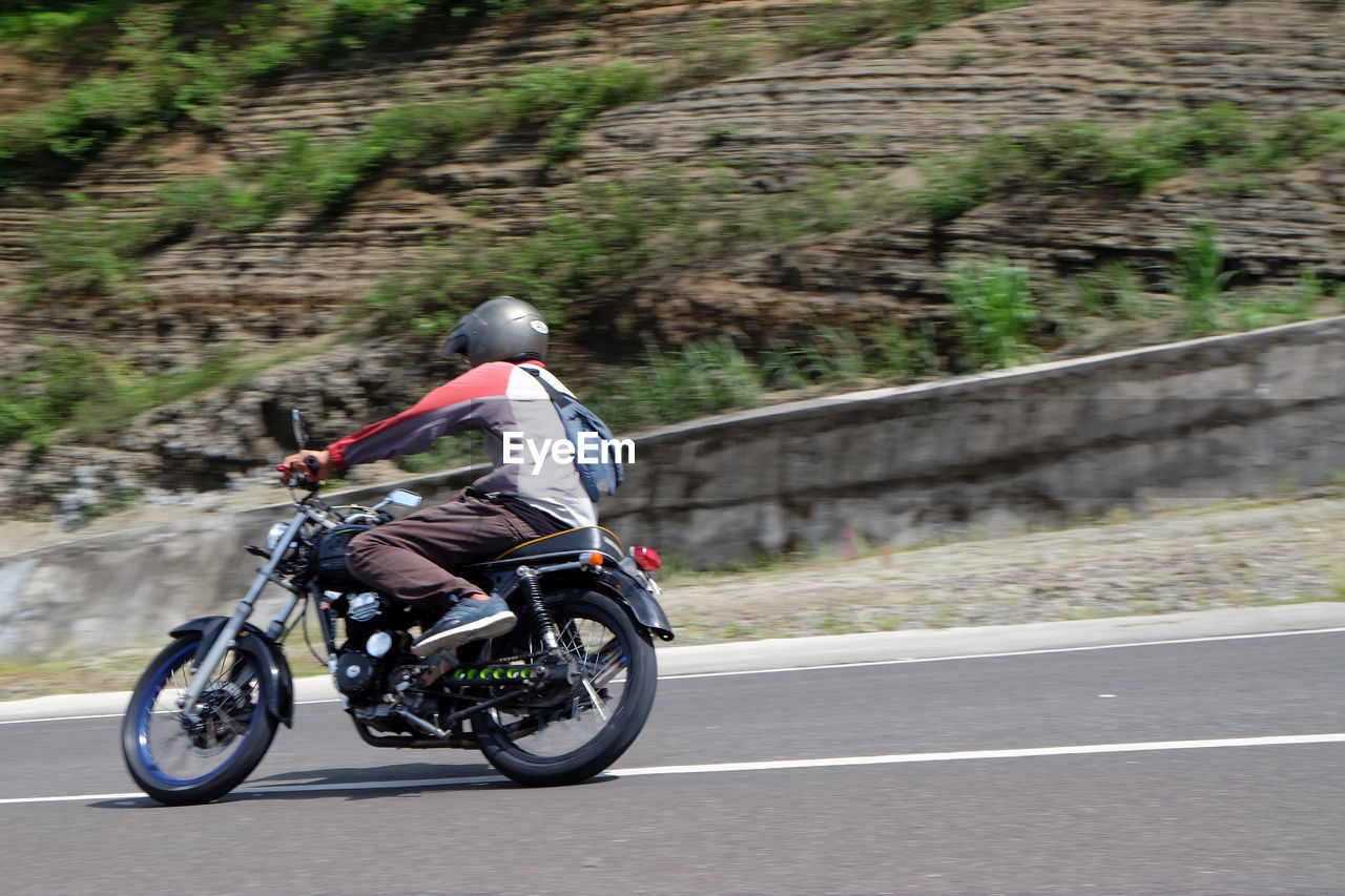 REAR VIEW OF MAN RIDING MOTORCYCLE