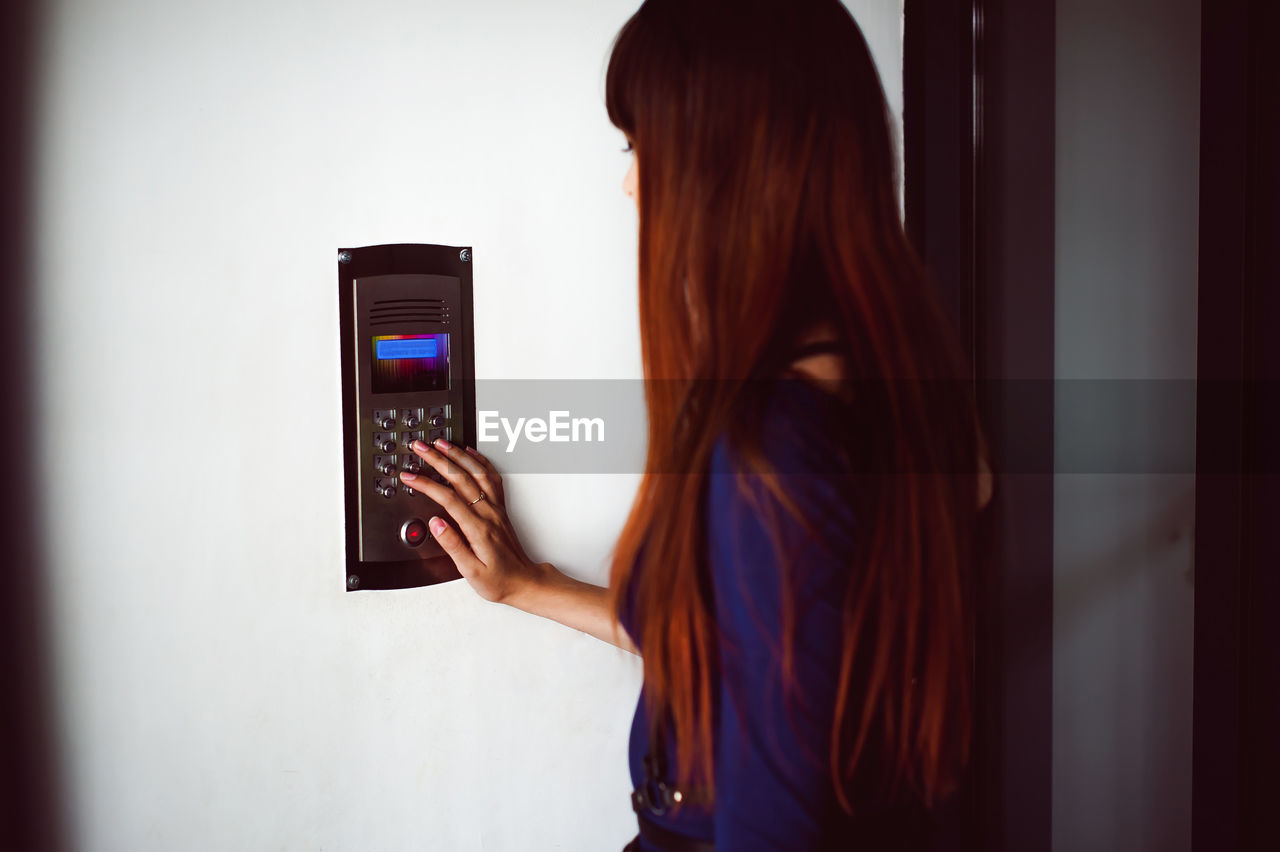 Woman using intercom on wall